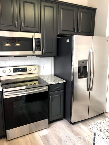 A black and silver kitchen with a refrigerator on the right.