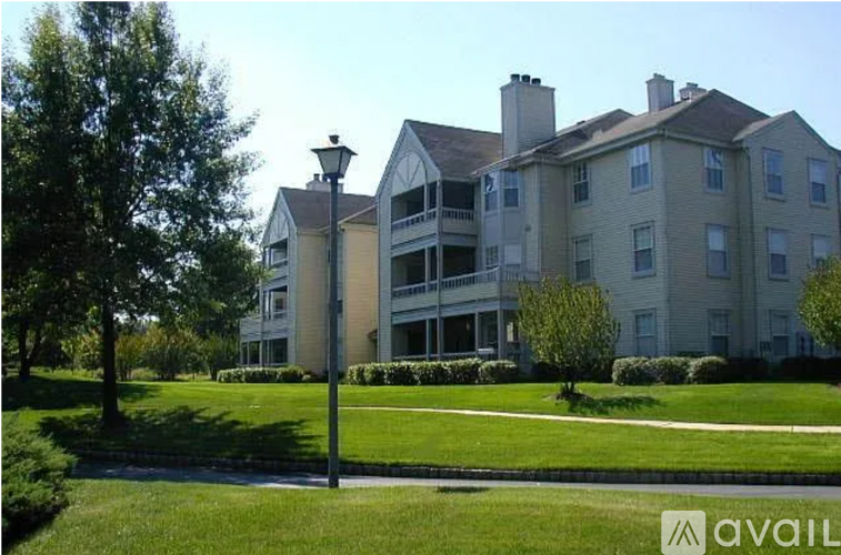A large, two-story building with a balcony on the second floor is surrounded by a well-manicured lawn and trees.