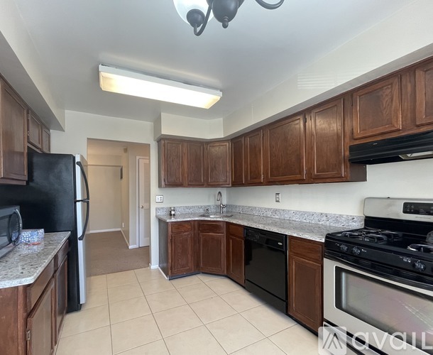 A kitchen with brown cabinets and black appliances.