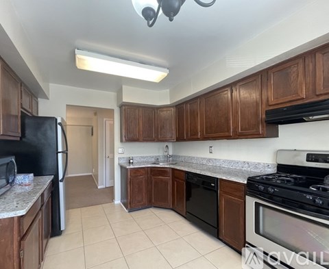 A kitchen with brown cabinets and black appliances.
