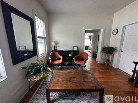 A living room with a wooden coffee table and three chairs.
