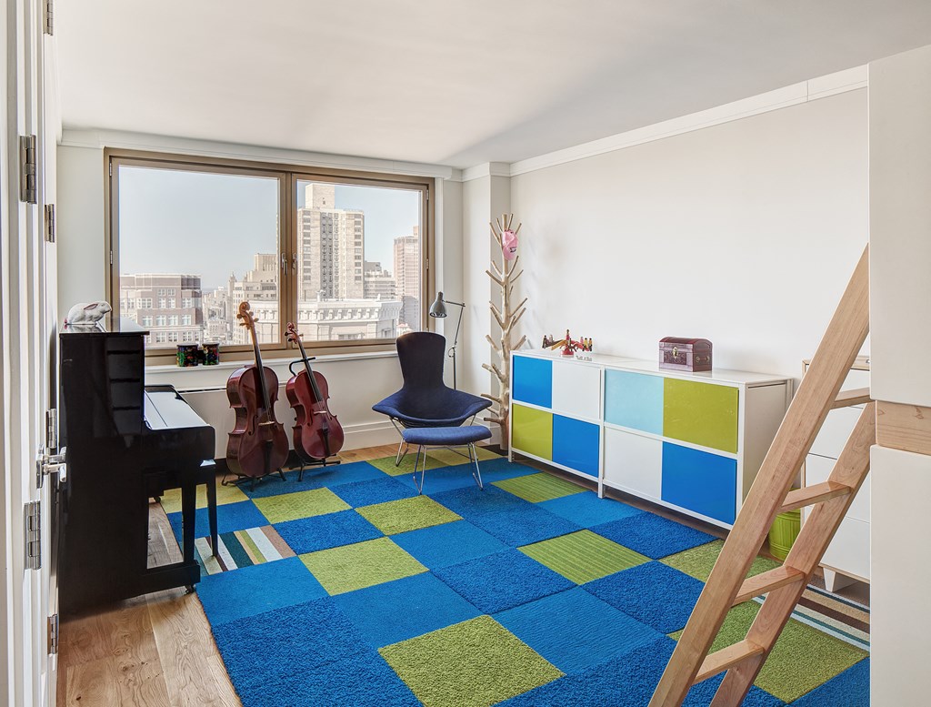 a living room with a piano and a blue and yellow rug