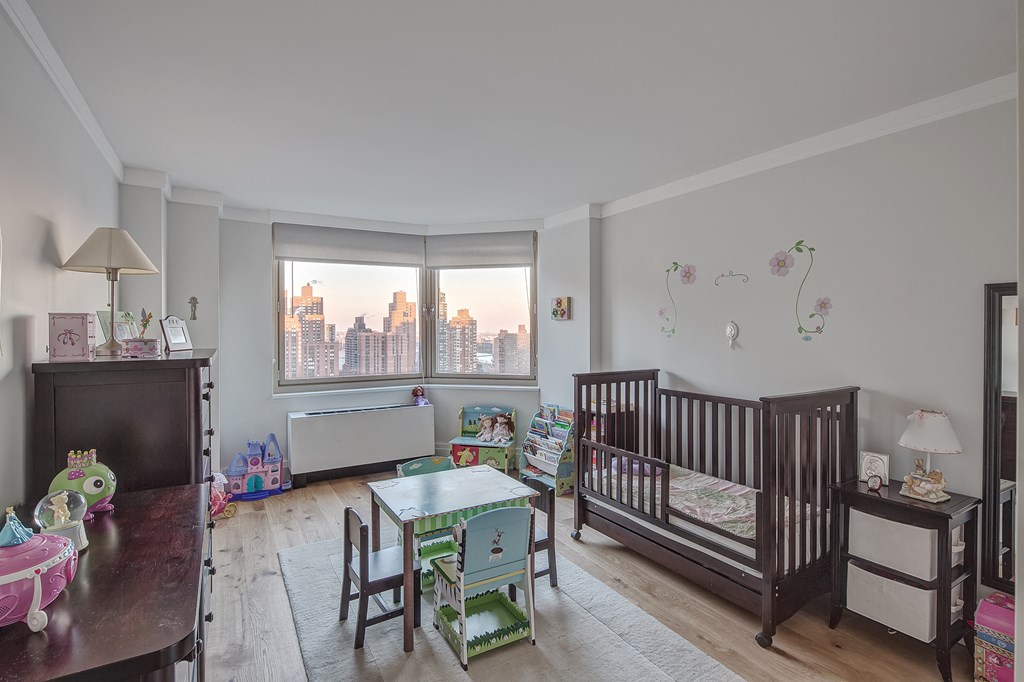 a nursery with a crib and a table and chairs in a room with a window