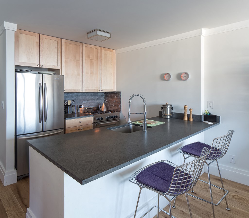 a kitchen with stainless steel appliances and a counter with two chairs