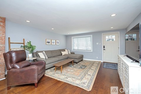 A living room with a brown leather chair and a grey couch.