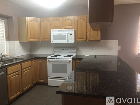 A kitchen with wooden cabinets and a black countertop.