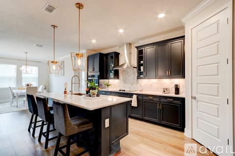A kitchen with black cabinets and a white island.