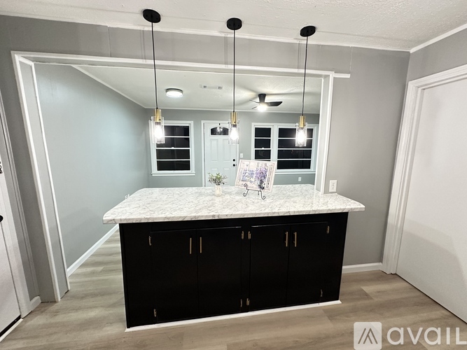 A kitchen with a marble countertop and black cabinets.