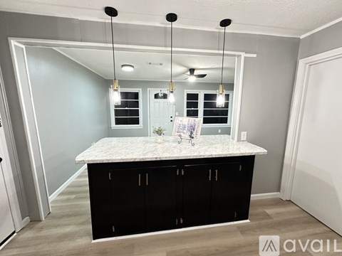 A kitchen with a marble countertop and black cabinets.