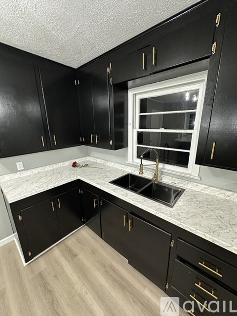 A kitchen with black cabinets and a marble countertop.