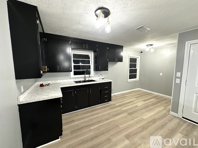 A kitchen with black cabinets and a white countertop is available.