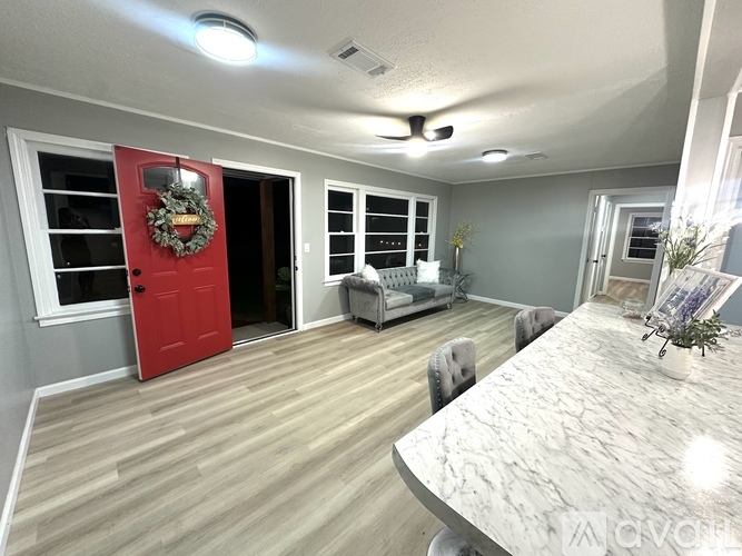 A living room with a red door and a grey wall.