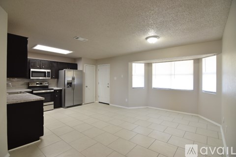 A kitchen with black cabinets and a refrigerator.