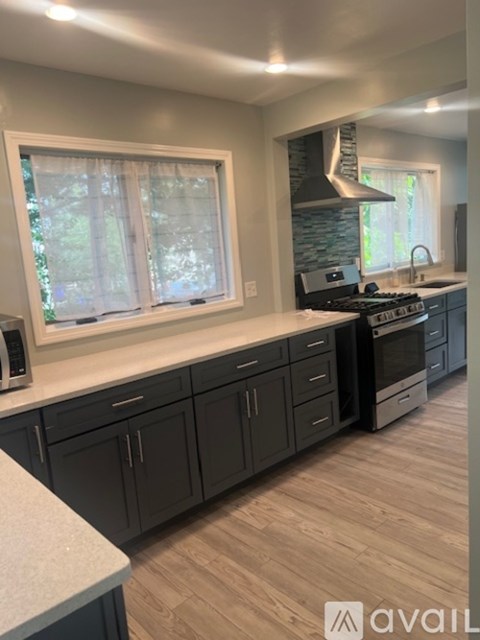 A kitchen with dark cabinets and a stove top oven.