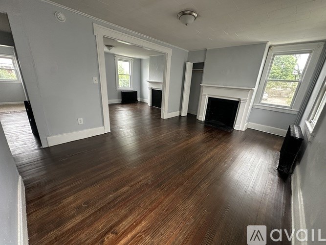 A spacious living room with wood flooring and a fireplace.