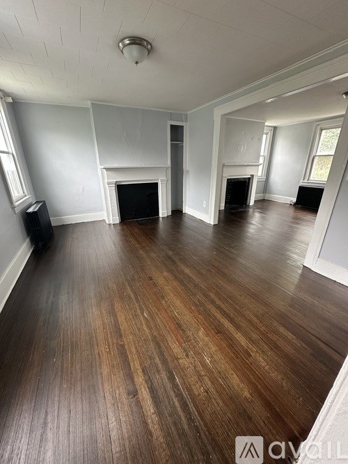 A living room with wood flooring and a fireplace.