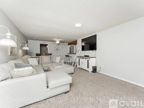 A living room with a white couch and a bar area in the background.