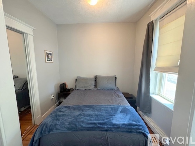 A bedroom with a bed, nightstand, and window.