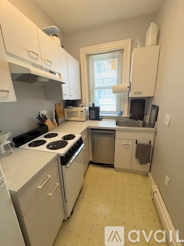 A kitchen with white cabinets and appliances.