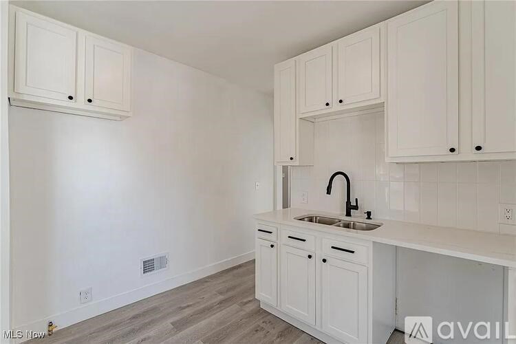 A kitchen with white cabinets and a sink.