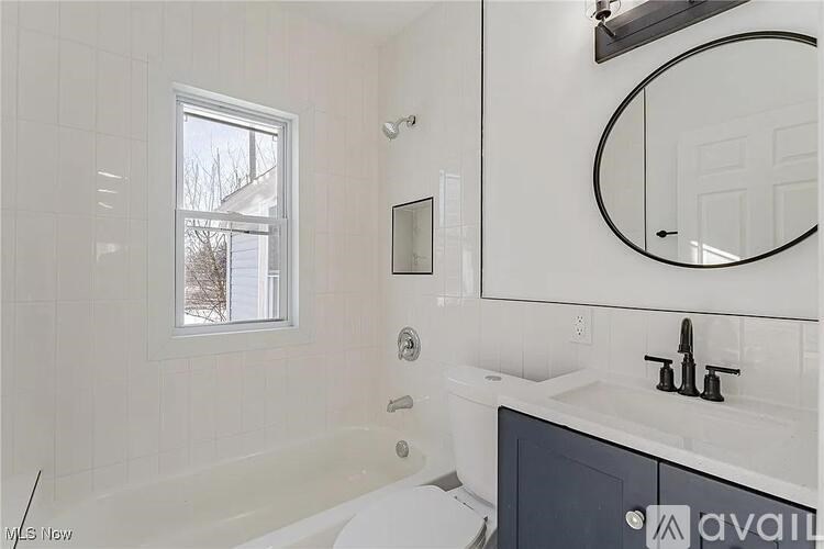 A bathroom with a white tub, sink, and mirror.