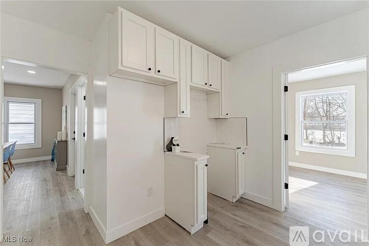 A kitchen with white cabinets and a refrigerator.