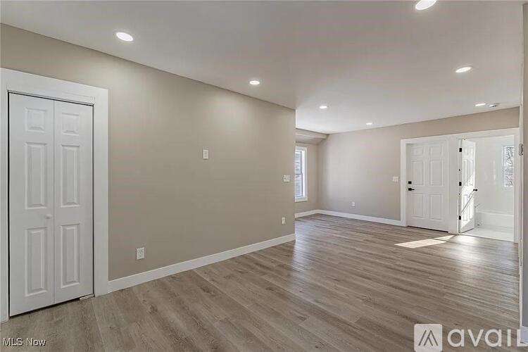 A spacious room with wood flooring and white walls.