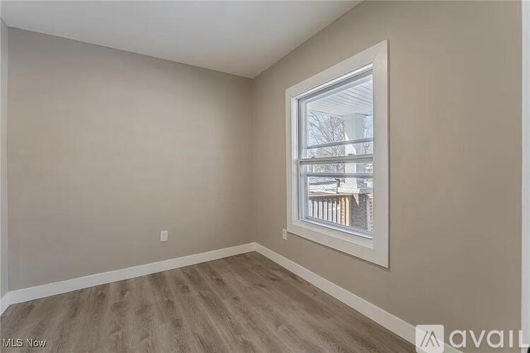 Empty room with a window and wooden flooring.