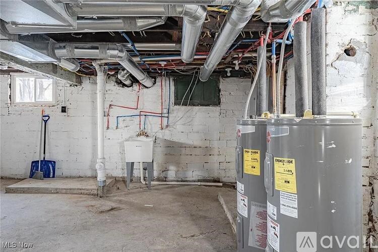 A dirty basement with a water heater and pipes.