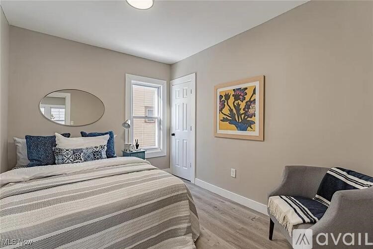 A bedroom with a bed, a chair, and a painting on the wall.