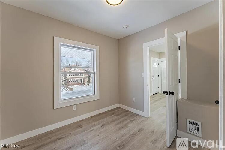 A room with a window showing a view of a house and a wall with a picture frame.