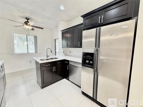 A kitchen with a stainless steel refrigerator and black cabinets.