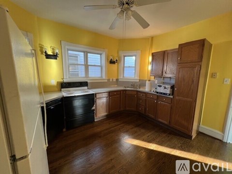 A kitchen with wooden cabinets and a black dishwasher.