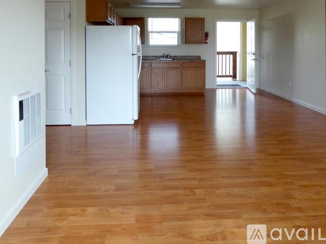 A kitchen with a white refrigerator and wooden floors.