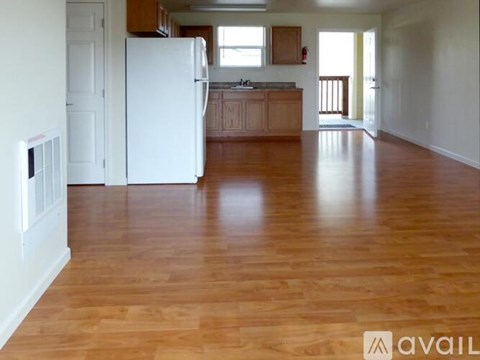 A kitchen with a white refrigerator and wooden floors.