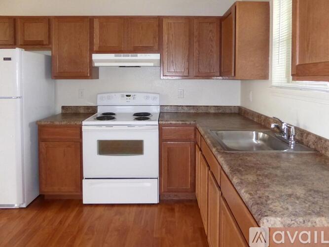 A kitchen with white appliances and wooden cabinets.