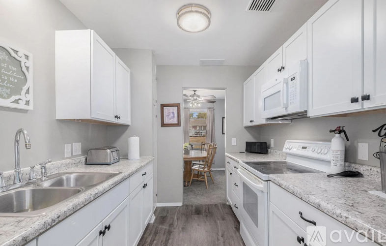A kitchen with white cabinets and a marble countertop.