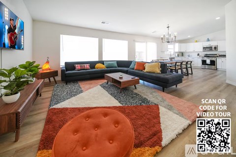 A living room with a black couch and a rug with a QR code on it.