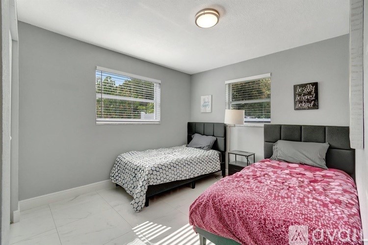A bedroom with two beds and a window with blinds.