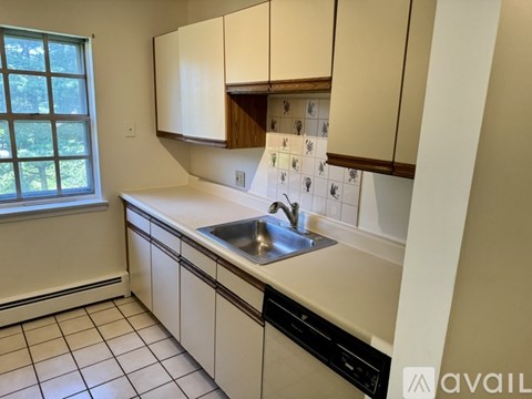 A kitchen with white cabinets and a window.