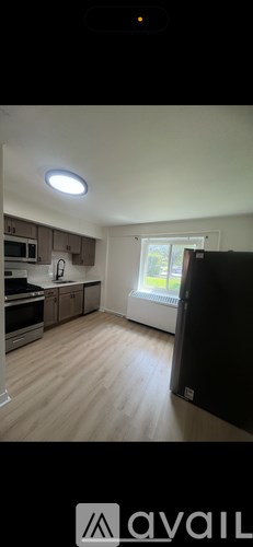 A kitchen with a black fridge and wooden floors.