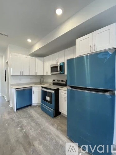A kitchen with a blue refrigerator and white cabinets.