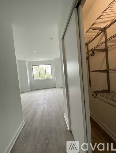 A room with a white door and a window with a view of trees outside.