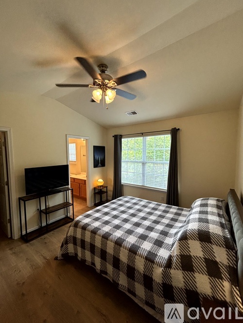 A bedroom with a checkered bedspread and a ceiling fan.