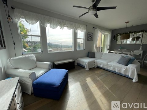 A living room with white furniture and a blue ottoman.