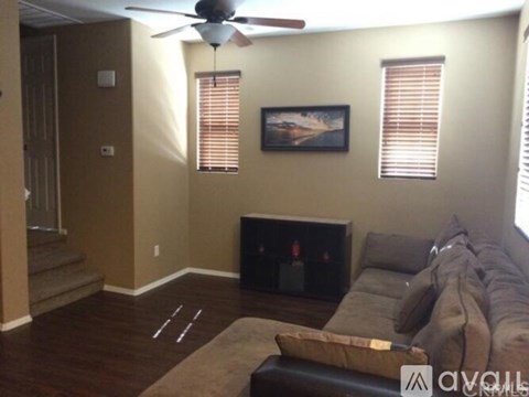 A living room with a brown couch and a painting on the wall.