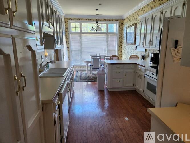 A kitchen with white cabinets and a wooden floor.