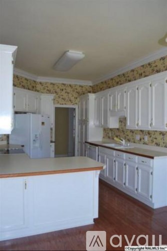 A kitchen with white cabinets and a floral wallpaper.