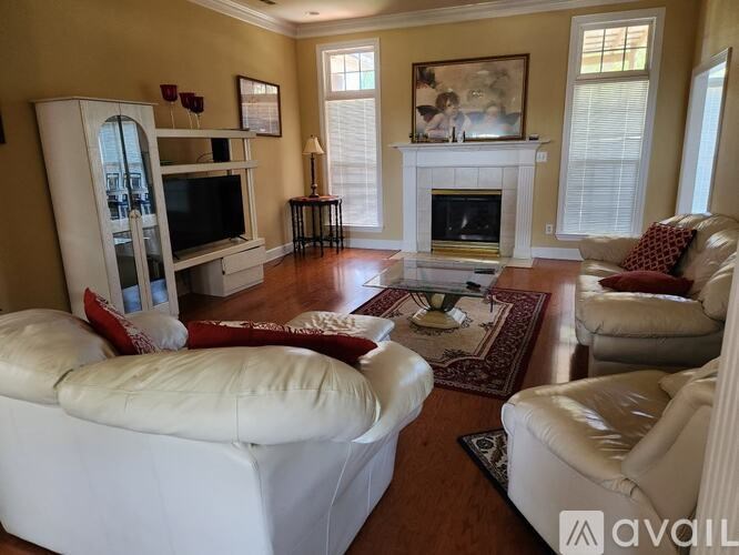 A living room with a white couch, a television, and a fireplace.