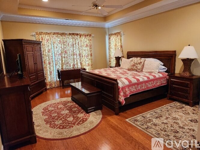 A bedroom with a large bed and a wooden dresser.